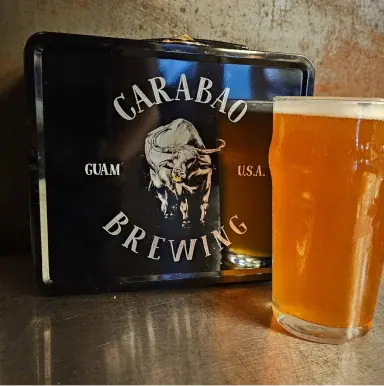 A Carabao Brewing lunch box next to a pint